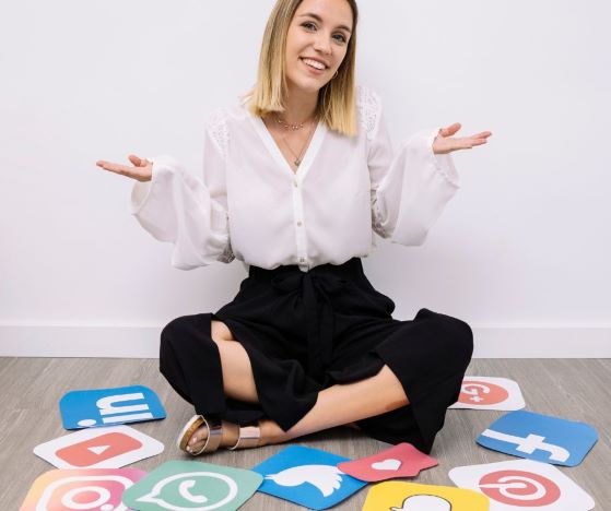 nainen istuu lattialla sosiaalisen median kanavien logojen keskellä
